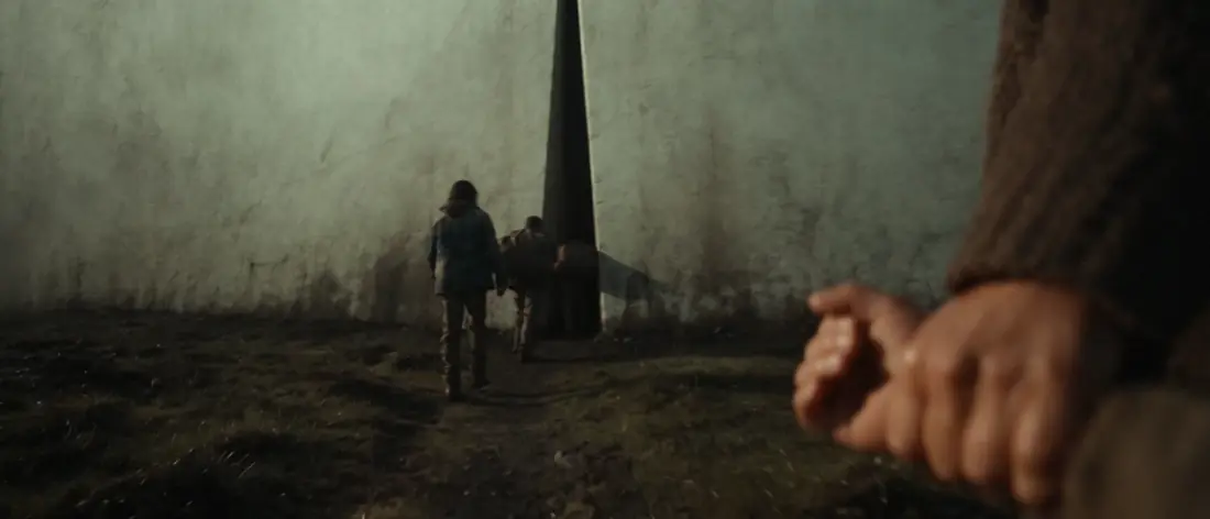 A child walks toward a spire at the foot of the wall