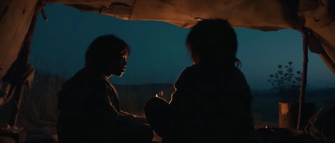The boys talk inside a tent at dusk